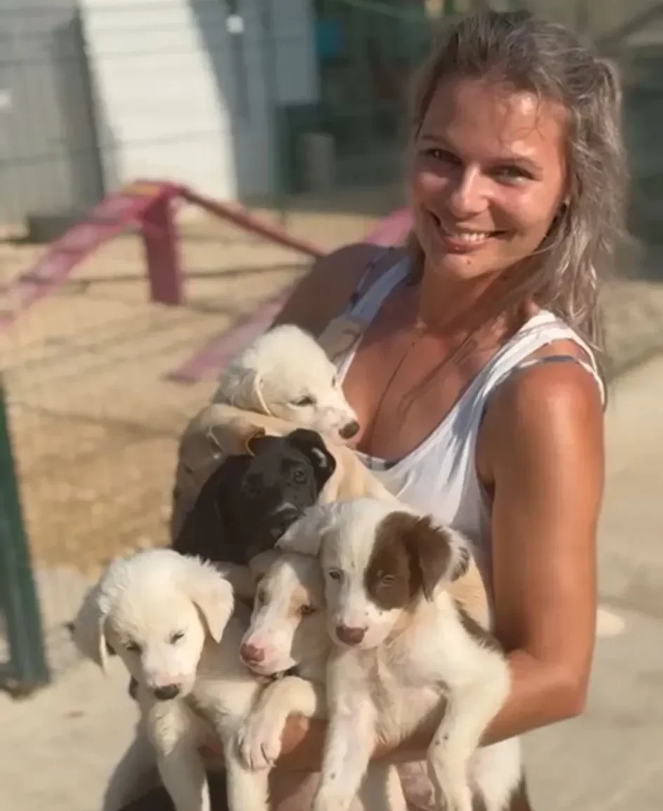 A Picture of a women holding several puppies 